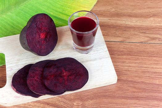 Fresh slices red beet root and beet root fruit juice in shot glass a wood background