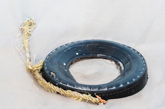 old tyre with rope on beach