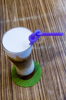 Cold capuccino in tall glass with straw