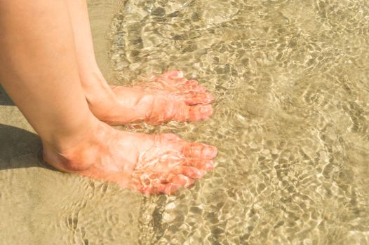 woman feet in water on beach