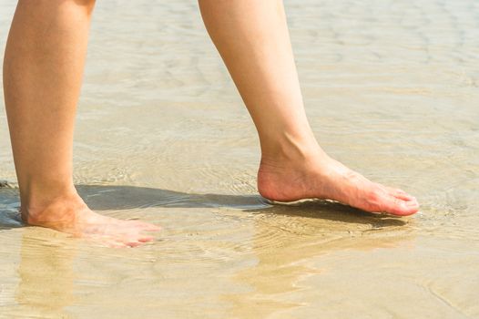 woman feet in water on beach