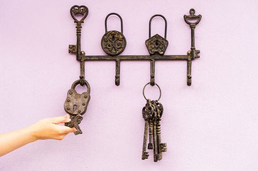 hand with brass antique skeleton keys hanging on pink wall