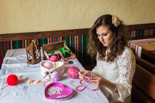 Girl makes balloon decoration with colored threads and ribbons