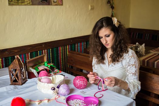 Girl makes balloon decoration with colored threads and ribbons