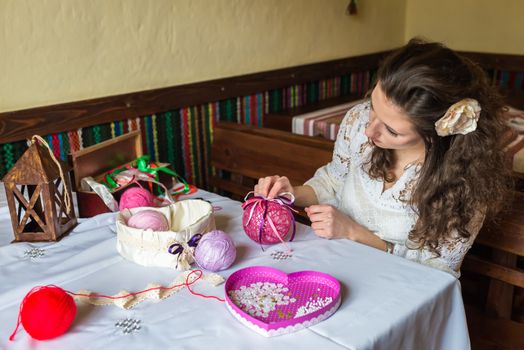 Girl makes balloon decoration with colored threads and ribbons