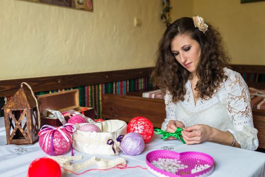 Girl makes balloon decoration with colored threads and ribbons