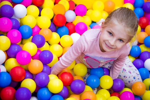 Girl in the playing room with many little colored balls