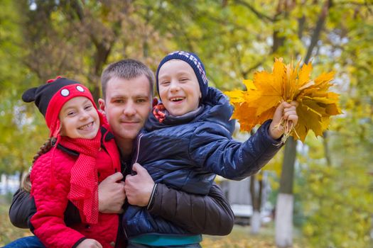 Happy father with two children in autumn park