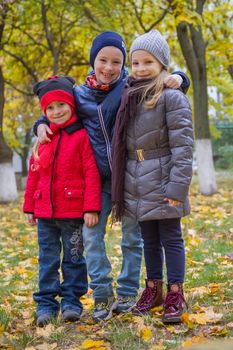 Three kids embracing among autumn park