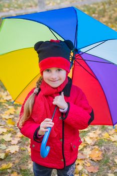 Girl with rainbow umbrella in autumn
