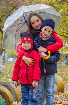 Mother with two kids under umbrella in autumn