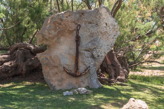 Old rusted ship anchor hanging on a stone in Majorca, Spain.