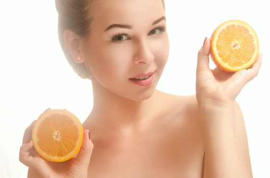Young beautiful smiling woman holding two halves of an orange White background