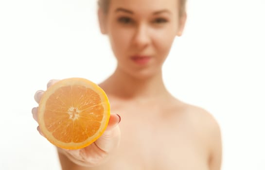 Young woman holding half an orange in front of her. White background