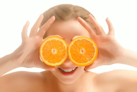 Young beautiful woman having fun and covering her eyes with orange slices. White background
