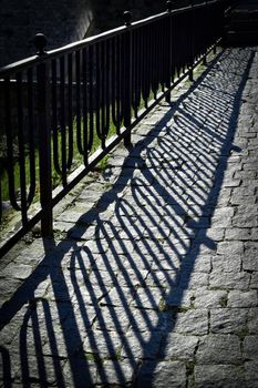 abstract background iron railing shadow on stone pavement