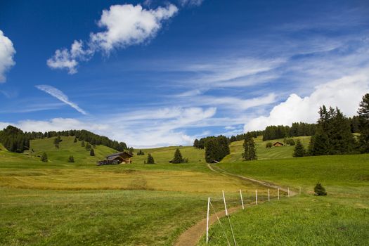 panoramic view of the Seiser Alm in a sunny day with blue sky and clouds with path in the foreground