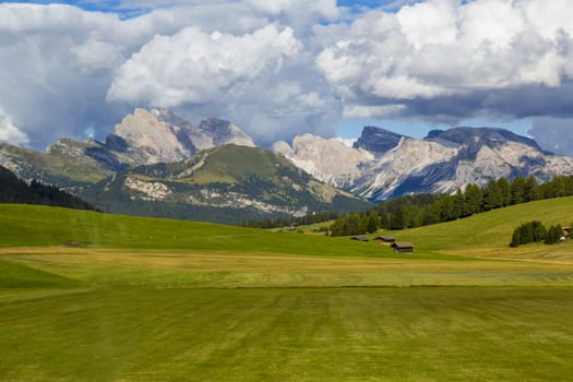 panoramic view of the Seiser Alm in a sunny day with blue sky and clouds with mountain range in the background