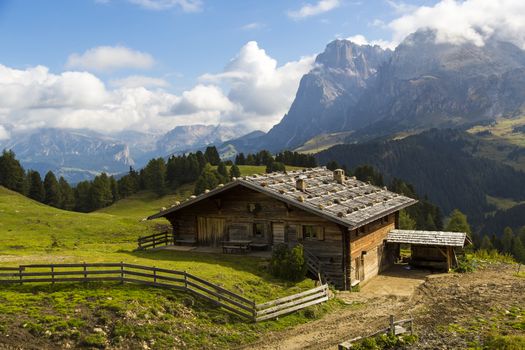 View of a mountain hut on a sunny day with mountains in the background