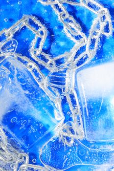 Metal chain under frozen water against blue background