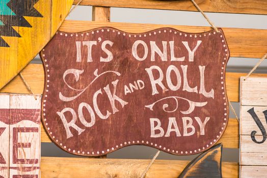 wooden board with the inscription 'It's only rock and roll baby'