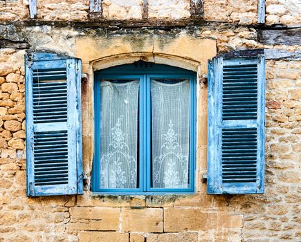 An ancient blue window on a stone wall