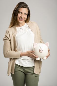 Beautiful and happy woman holding a piggy bank, isolated over white background