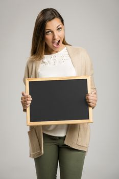 Beautiful and happy woman holding a chalkboard, with copy-space