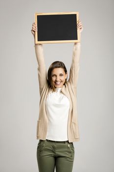 Beautiful and happy woman holding and showing a chalkboard very high