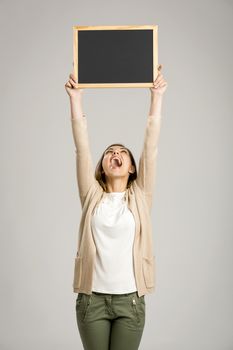 Beautiful and happy woman holding and showing a chalkboard very high