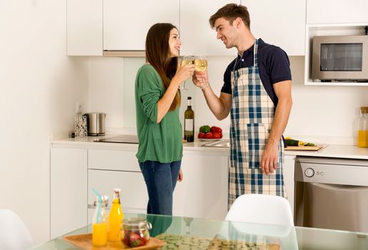 Young couple on the kitchen enjoying a  glass of white wine