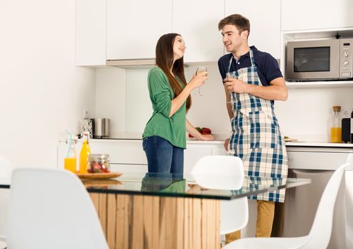 Young couple on the kitchen enjoying a  glass of white wine