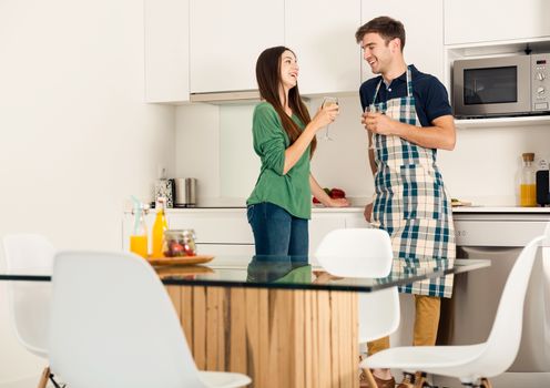 Young couple on the kitchen enjoying a  glass of white wine