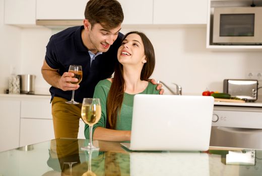 Young couple tasting wine and the women working on a laptop