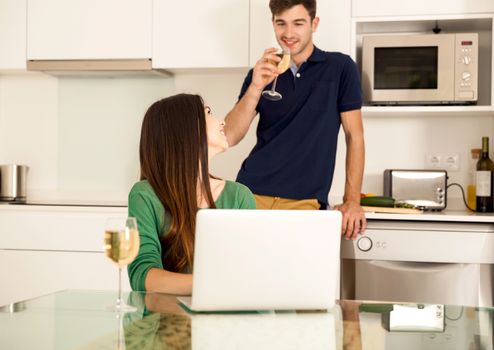 Young couple tasting wine and the women working on a laptop