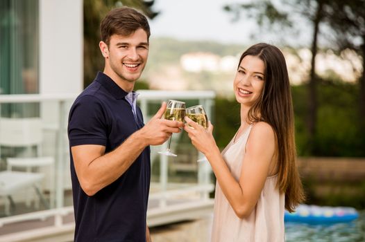Young couple tasting wine near by the pool on a hotel