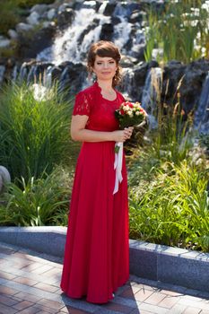 Girl in evening red dress in a warm summer day