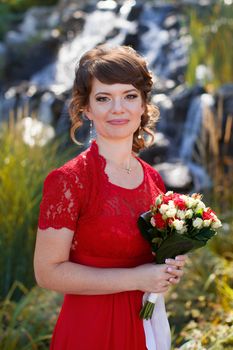 Girl in evening red dress in a warm summer day