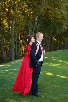 Man and woman standing embraced in a meadow in the park on a warm day