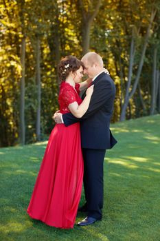 Man and woman standing embraced in a meadow in the park on a warm day