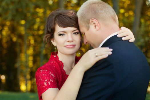 Man and woman standing embraced in a meadow in the park on a warm day