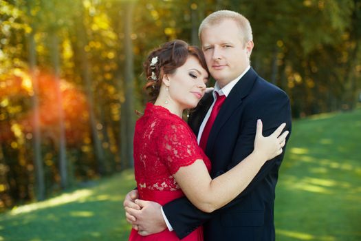 Man and woman standing embraced in a meadow in the park on a warm day