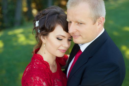 Man and woman standing embraced in a meadow in the park on a warm day