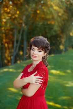 Girl in evening red dress in a warm summer day