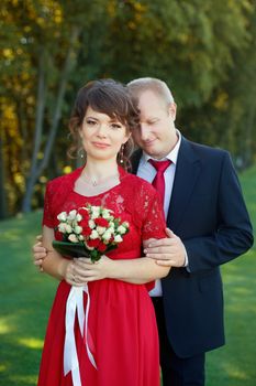 Man and woman standing embraced in a meadow in the park on a warm day