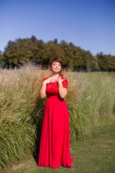 Girl in evening red dress in a warm summer day