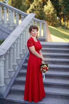 Girl in evening red dress in a warm summer day