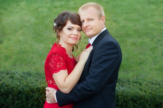 Man and woman standing embraced in a meadow in the park on a warm day