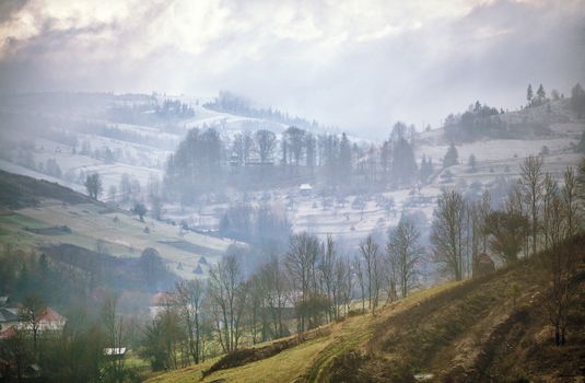 Late autumn misty morning in a village. First Snow in mountains