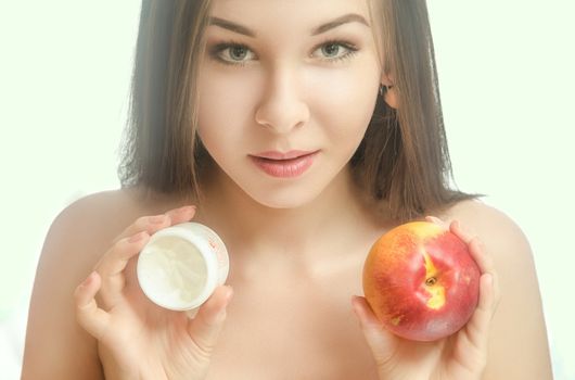 Young tender woman with her hair holding a peach and cream. White background